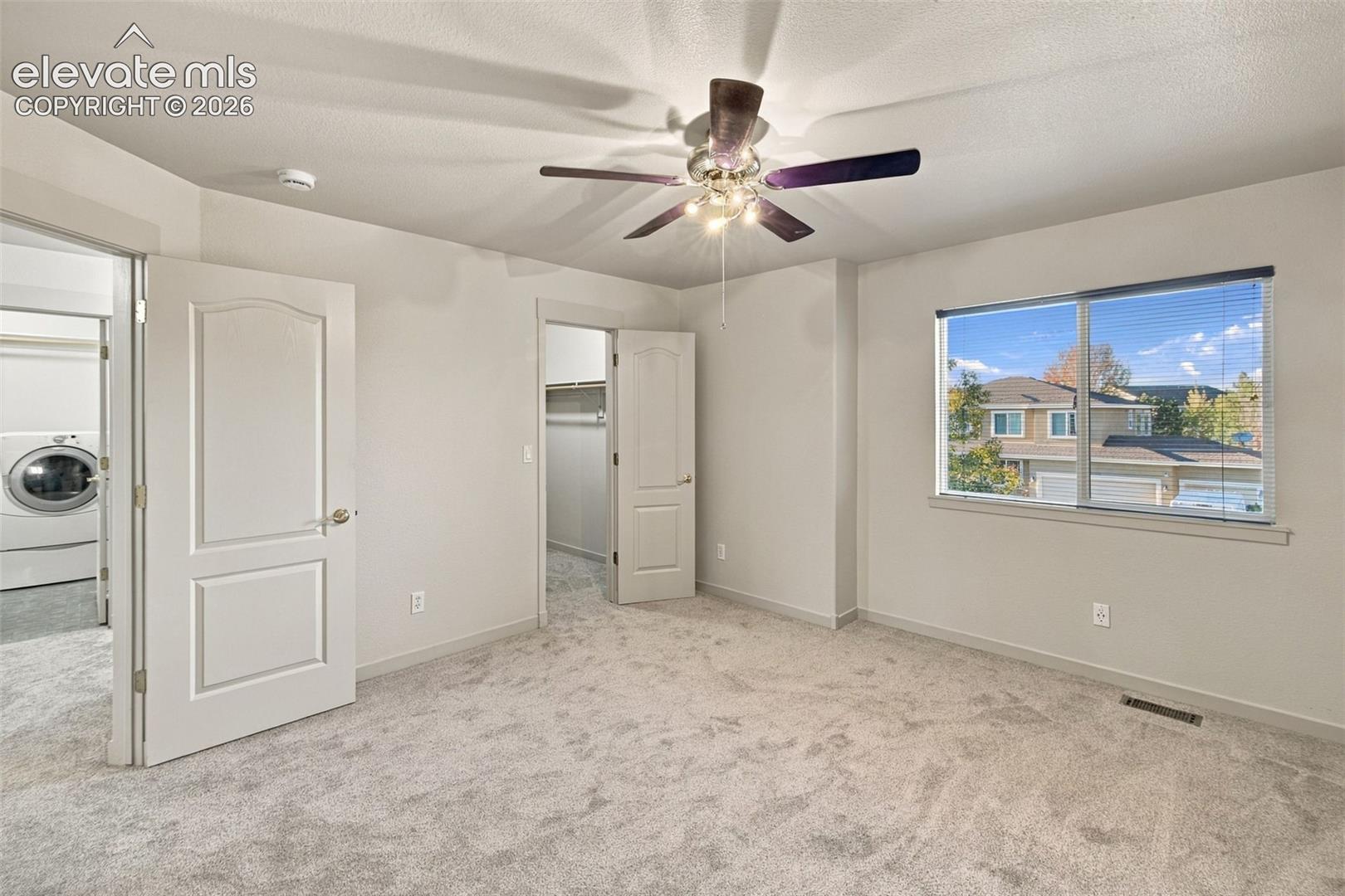 Room featuring neutral carpeting, a central multi-blade ceiling fan with integrated lighting, and a window with exterior exposure