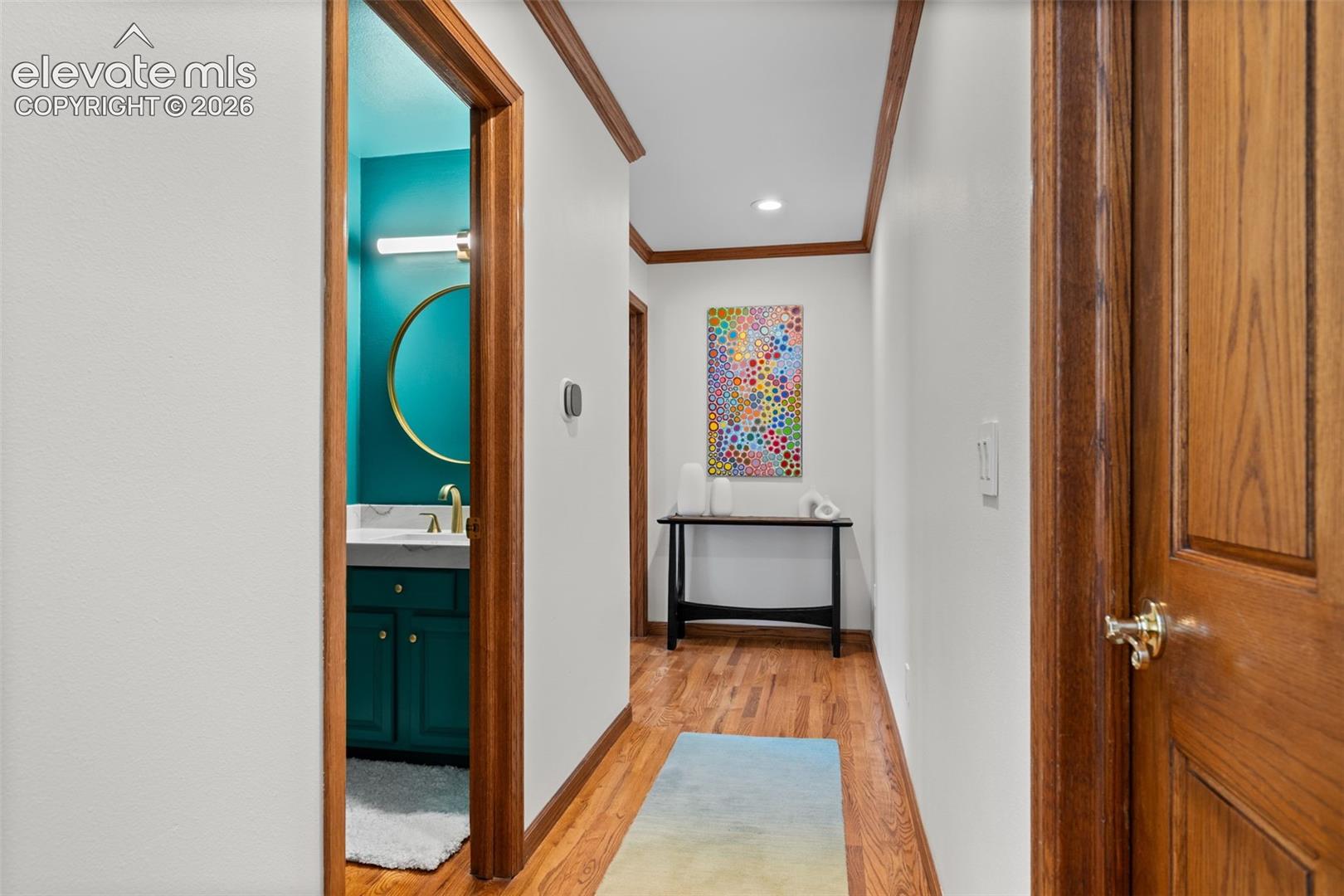 Hallway featuring wood-finish flooring, white walls, and wood trim