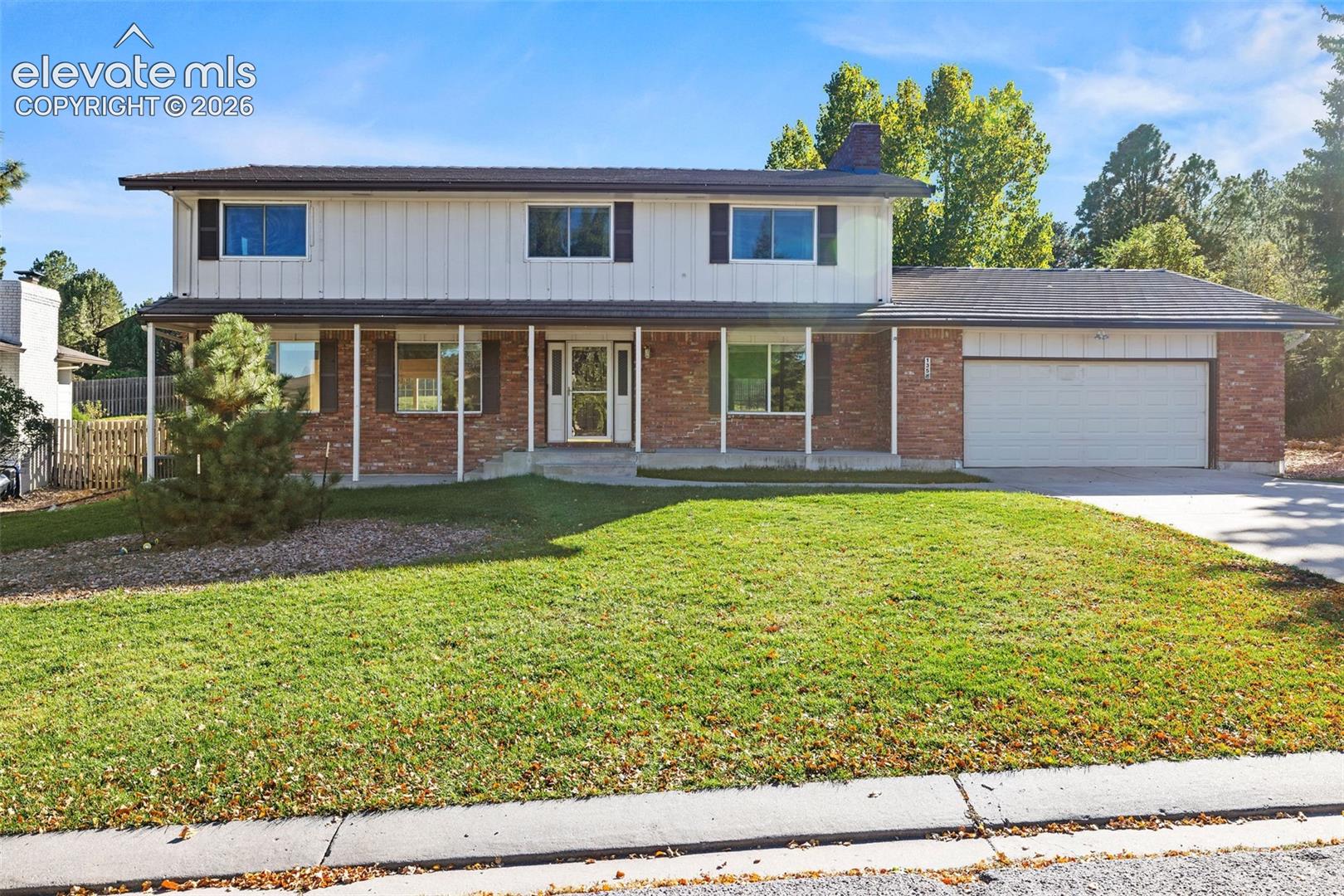 Two-story residence featuring a combination of brick and vertical siding exterior, a covered front porch, and an attached two-car garage
