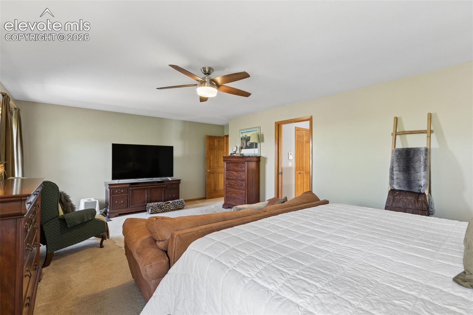 Spacious interior featuring neutral wall tones, wall-to-wall carpeting, and a central ceiling fan with integrated lighting