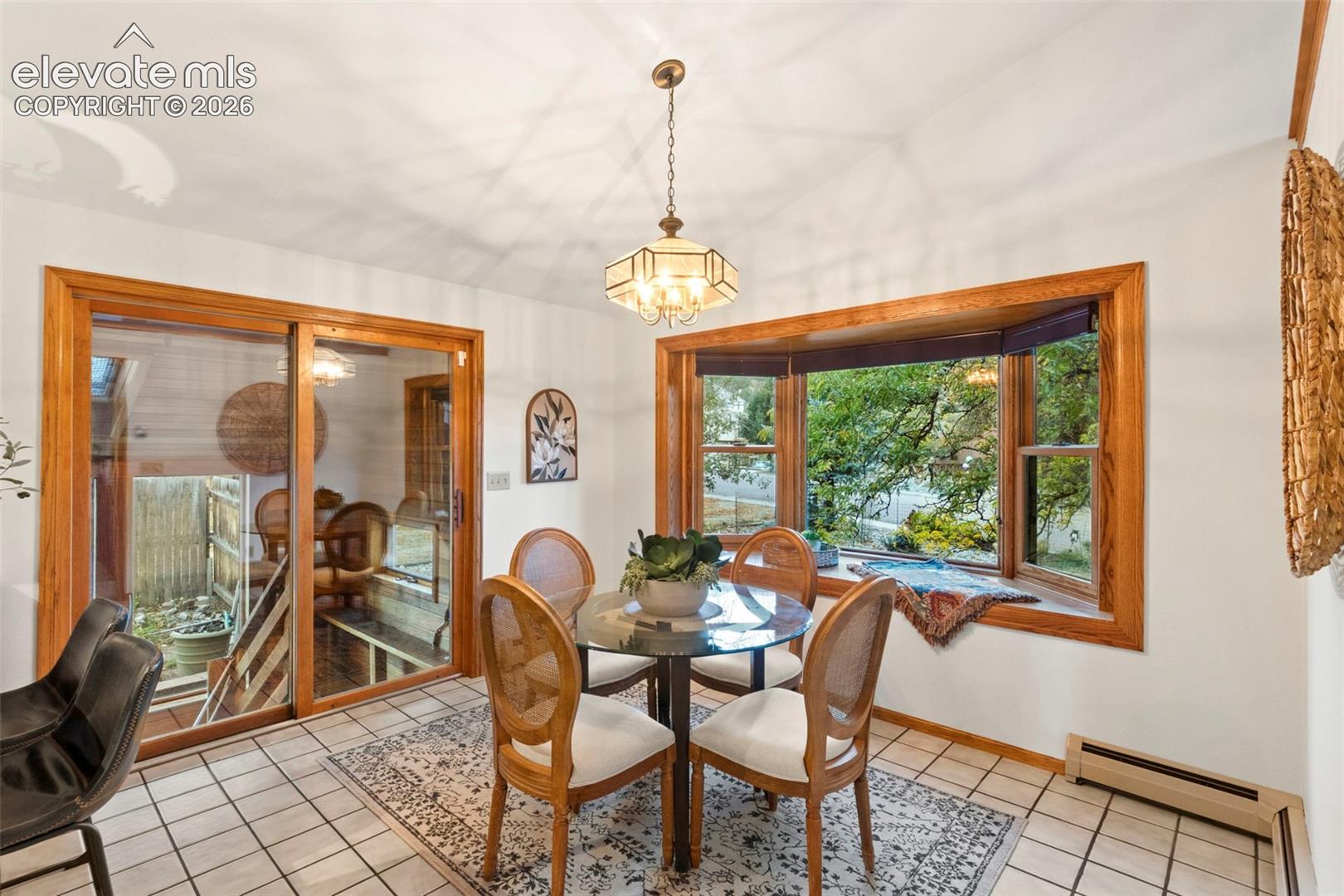 Dining area featuring a bay window with wood trim, ceramic tile flooring, a multi-light chandelier, and a sliding glass door