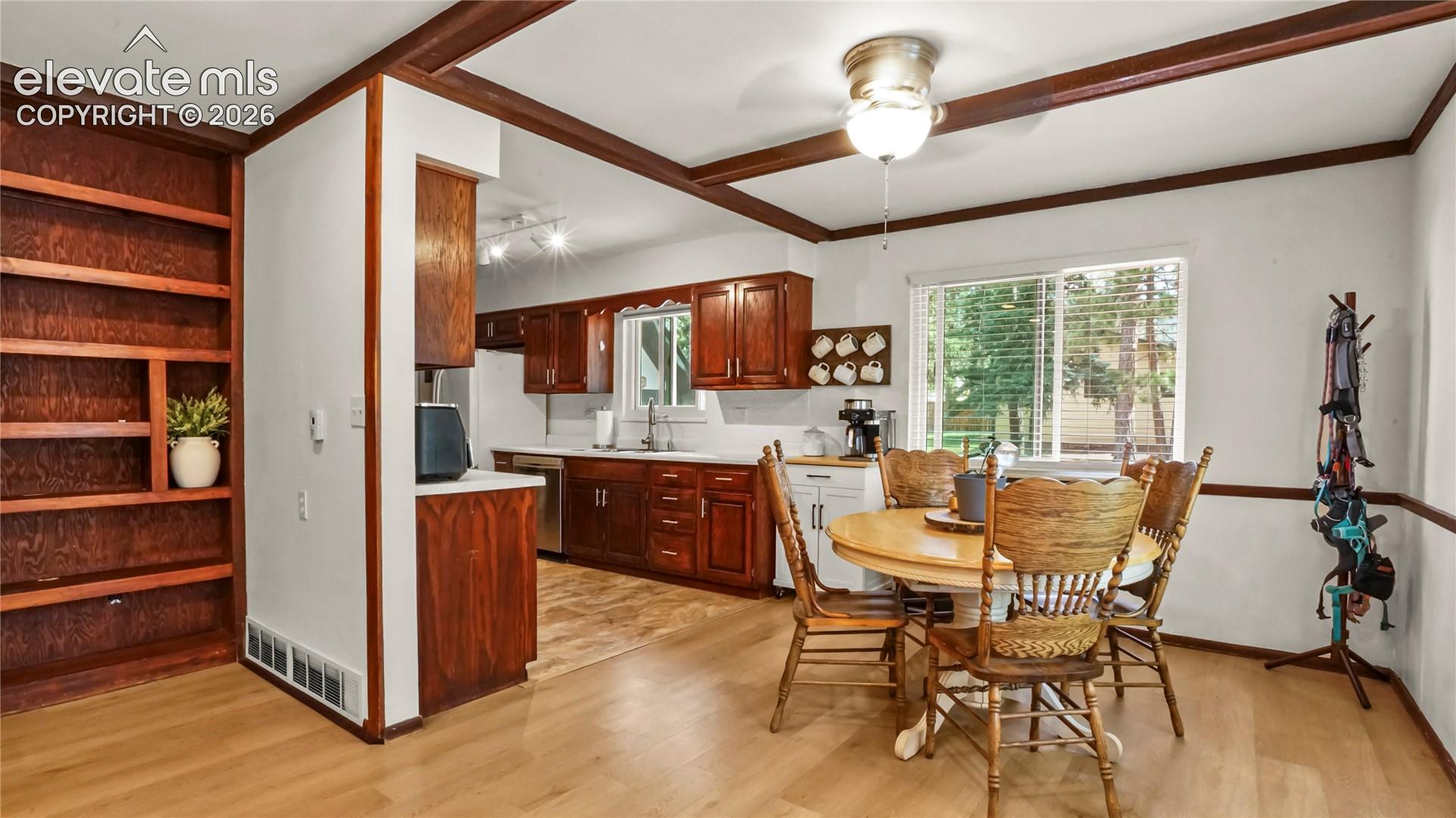 Kitchen with wood-finish cabinetry, stainless steel appliances, and a white subway tile backsplash, LVP flooring