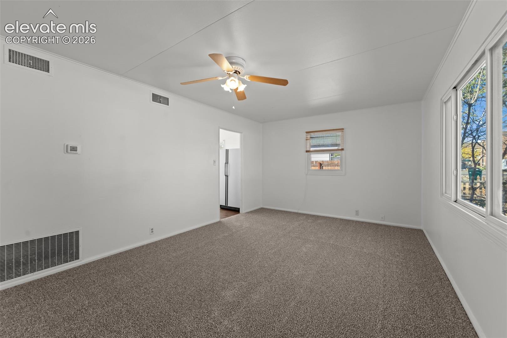 Interior room featuring wall-to-wall carpeting, a ceiling fan with integrated lighting, and multiple windows