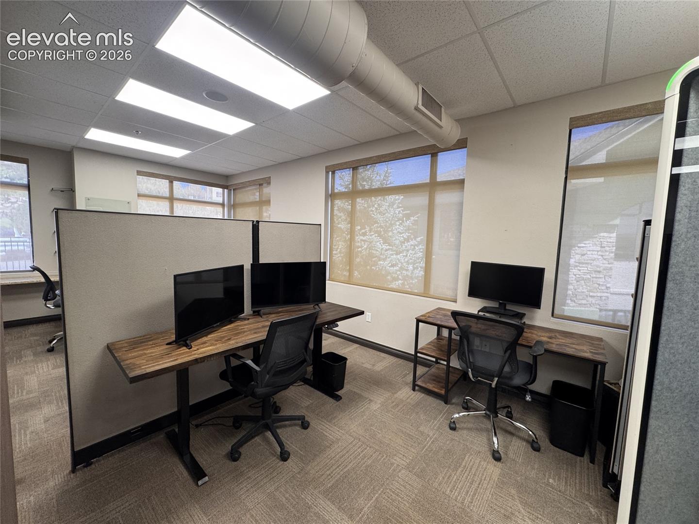 Recessed ceiling lighting, exposed ductwork, multiple windows with roller shades, carpeted flooring, and modular partition walls