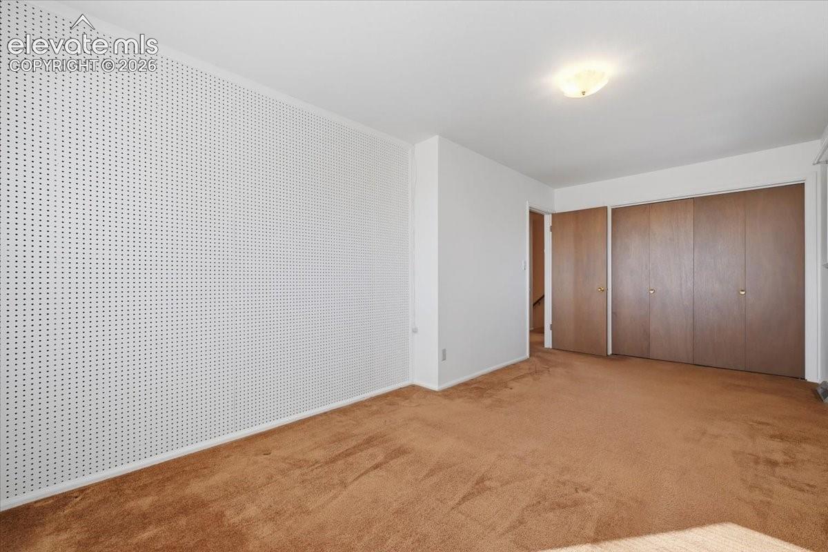 Room featuring carpeted flooring, a textured wall treatment, flush-mount ceiling lighting, and wood-finish closet doors