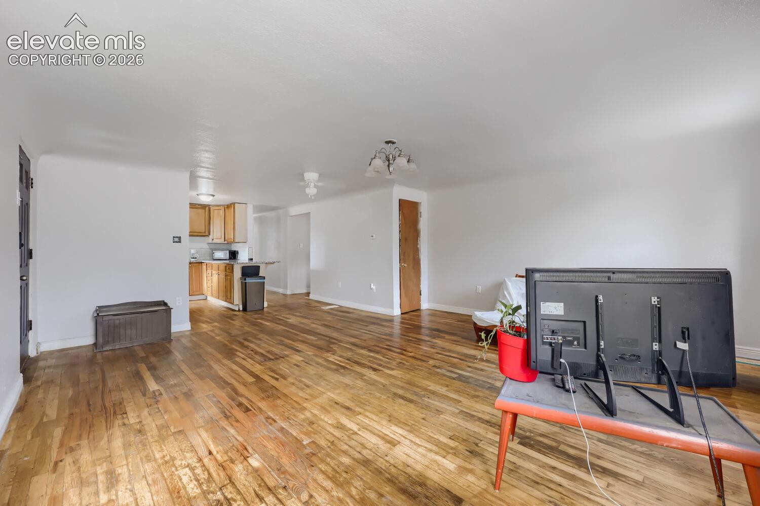 Wood-finish flooring throughout, light neutral wall paint, and overhead lighting fixture