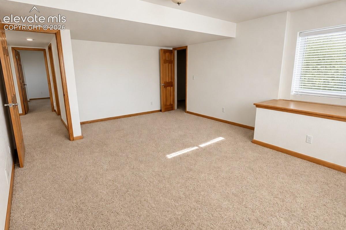 Basement bedroom 2/2 or workout area. Neutral tone carpeting with white walls and wood-finish trim