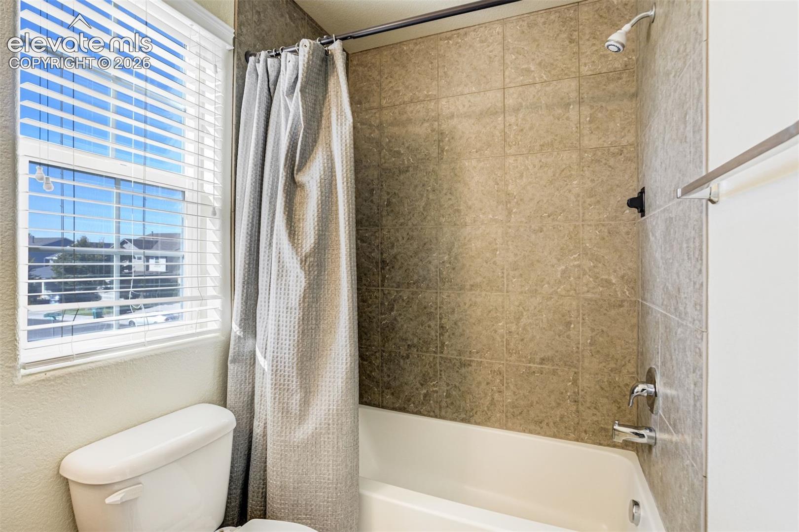 Full Bath on Upper level.  Bathtub with a tiled surround, a white toilet, and a window with blinds