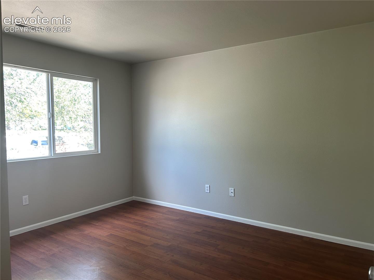 Interior space featuring wood-finish flooring, neutral wall paint, and a sliding window