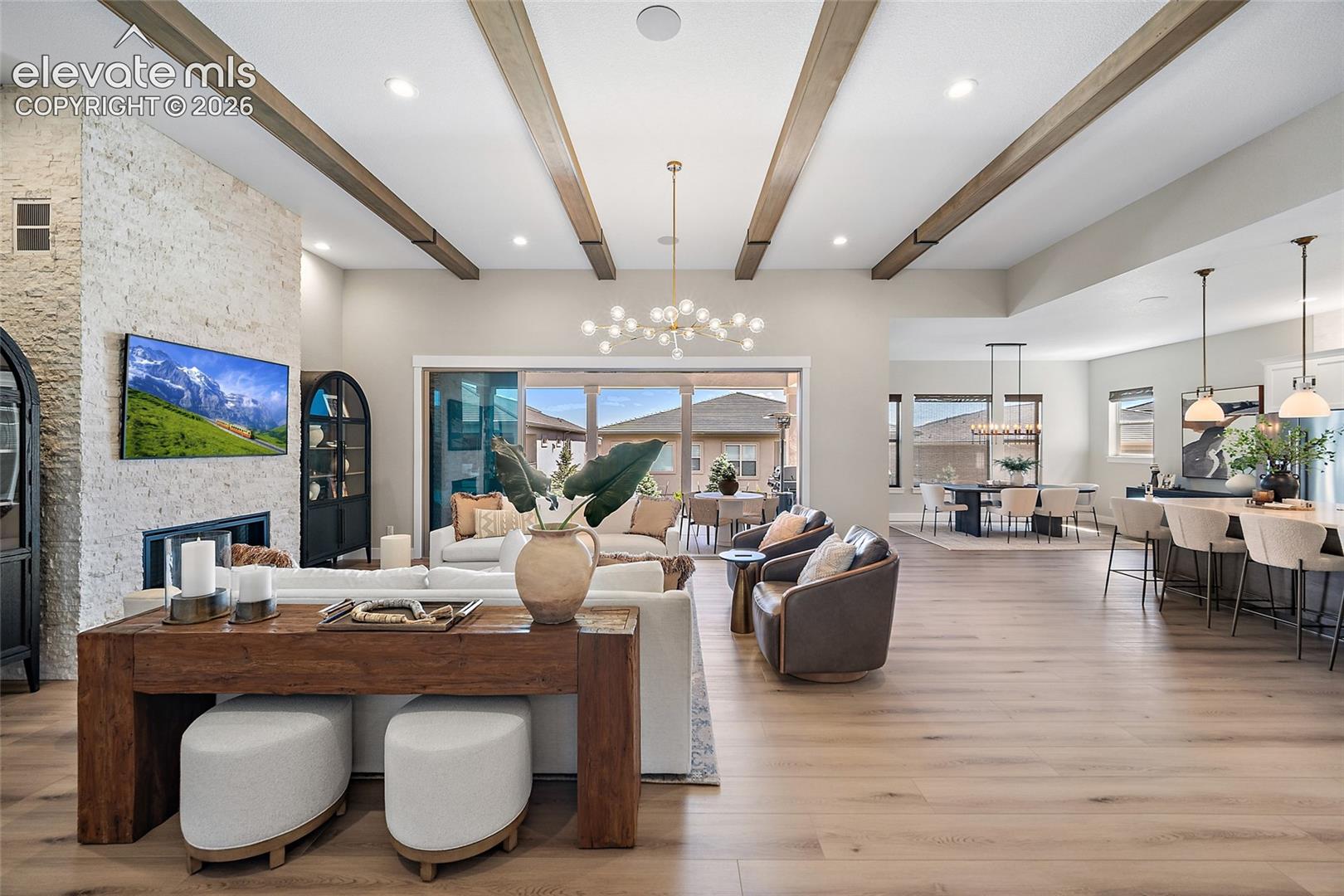 wood-finish beams, integrated fireplace with stone-finish surround, wood-finish flooring, sliding glass door, and recessed lighting