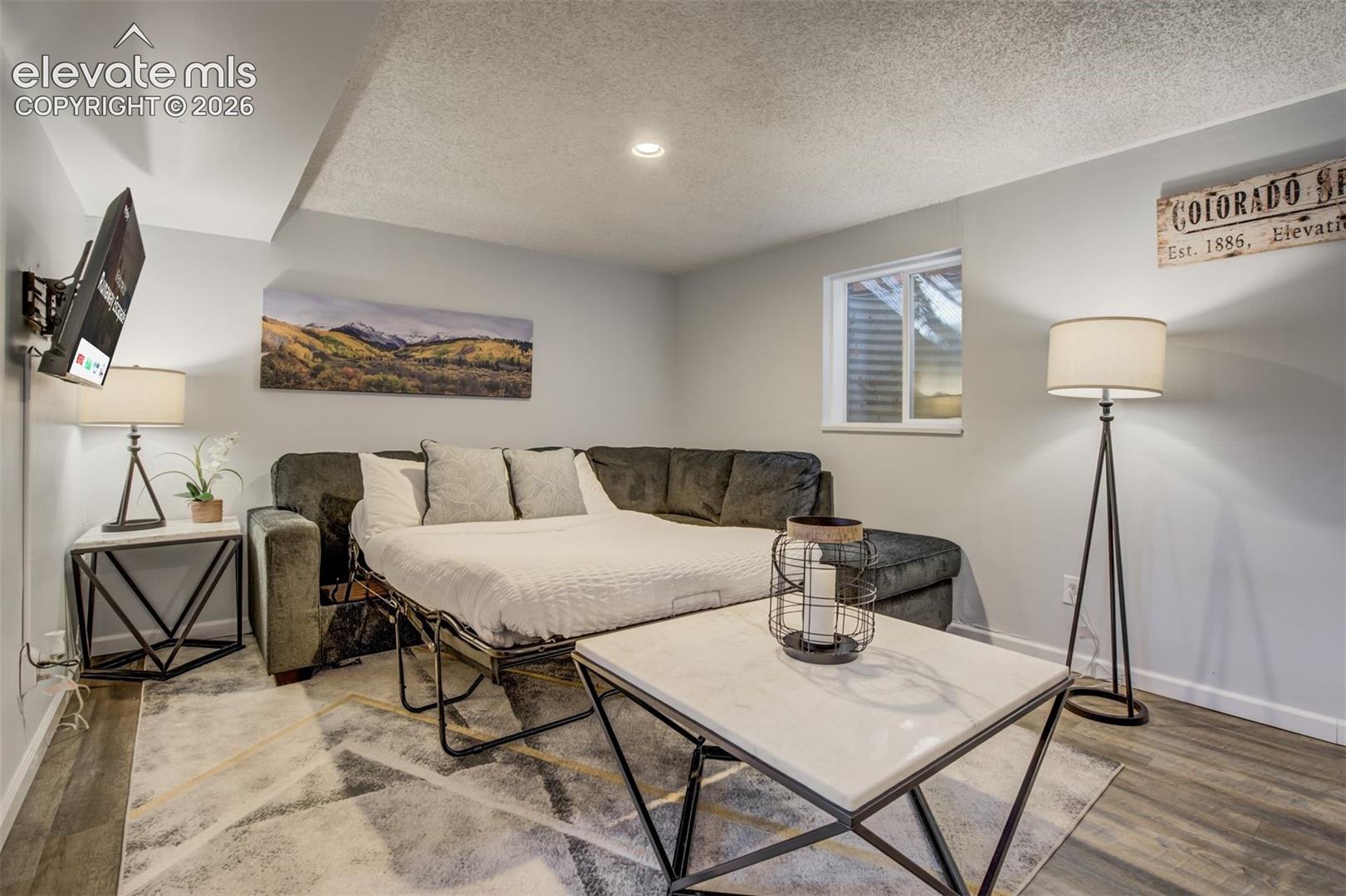 Recessed lighting illuminates the space, featuring wood-finish flooring and a window with blinds
