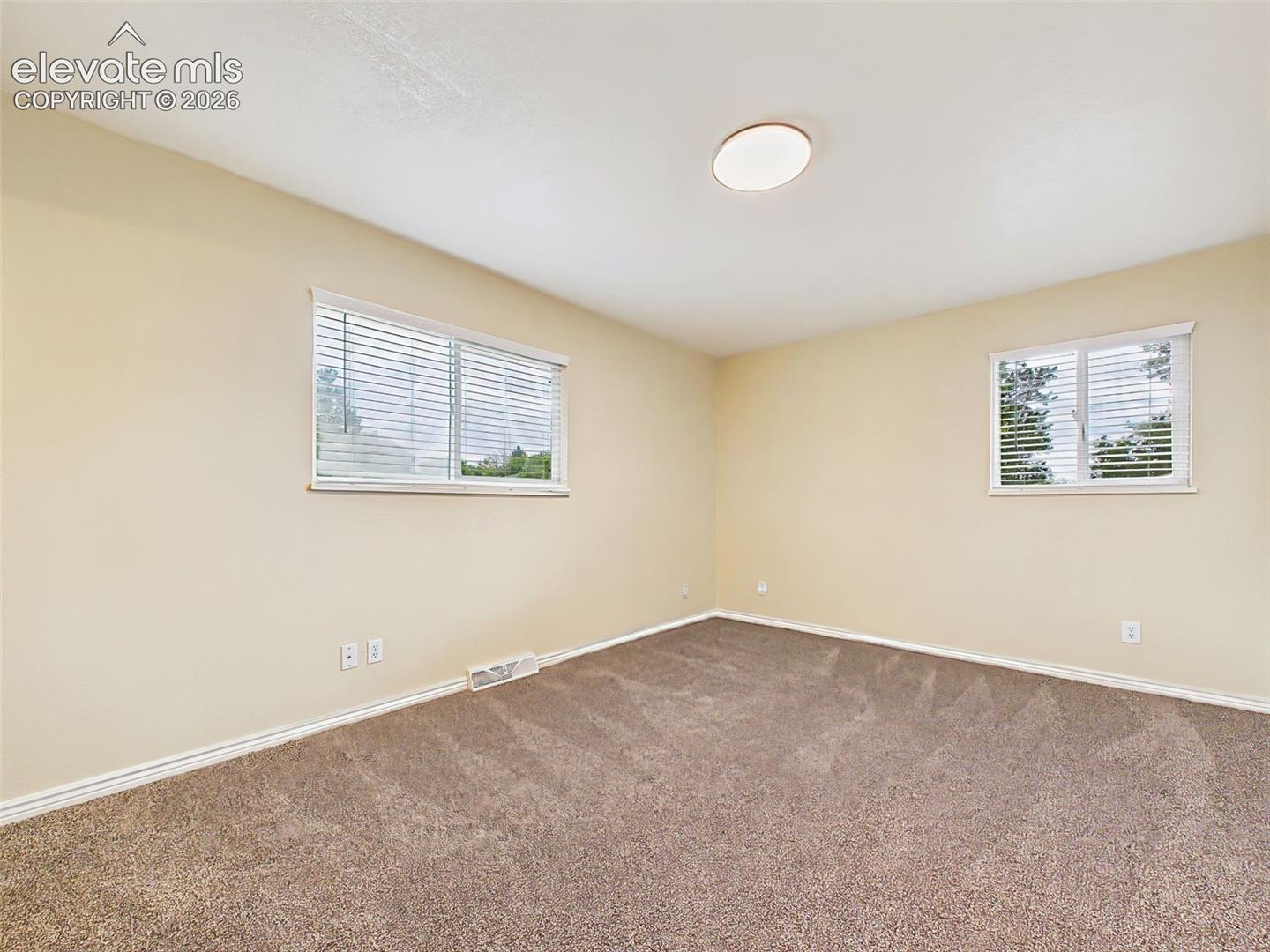 Bright and inviting primary bedroom offering plush carpeting, multiple windows, and a spacious retreat with a peaceful ambiance.

