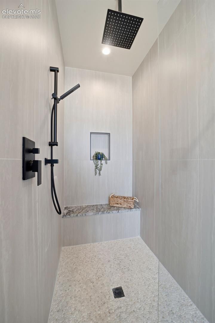Walk in shower with bench and glass door.