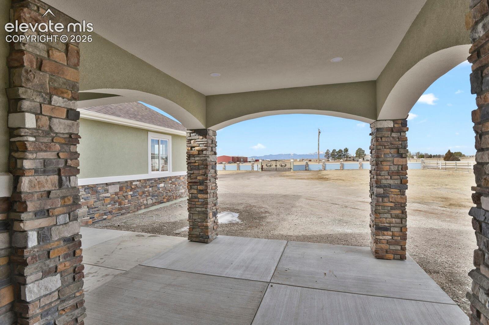 Arched entryway featuring stone pillars and a concrete pad