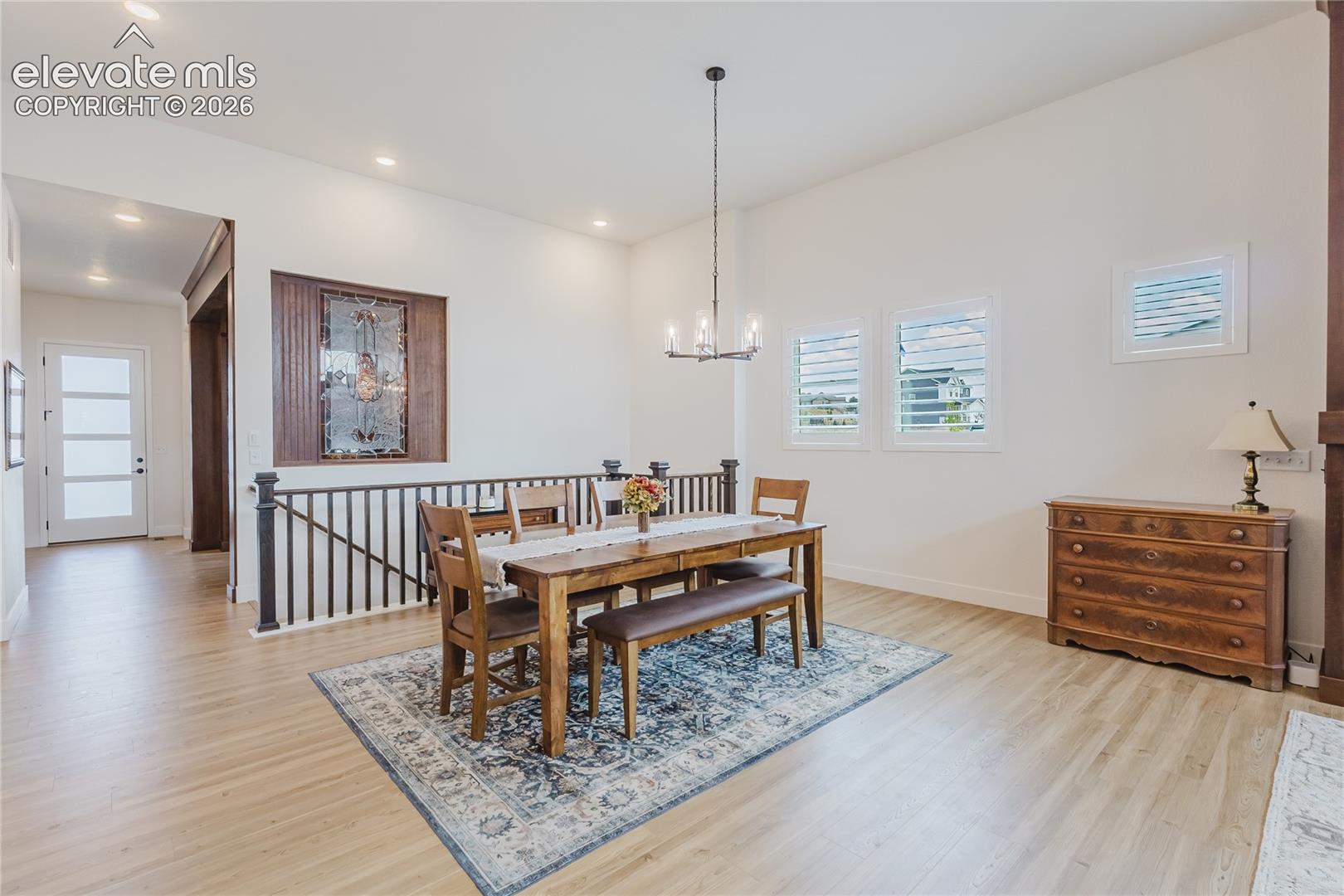 High ceilings, multiple windows with plantation shutters, recessed lighting, and a decorative stained glass panel