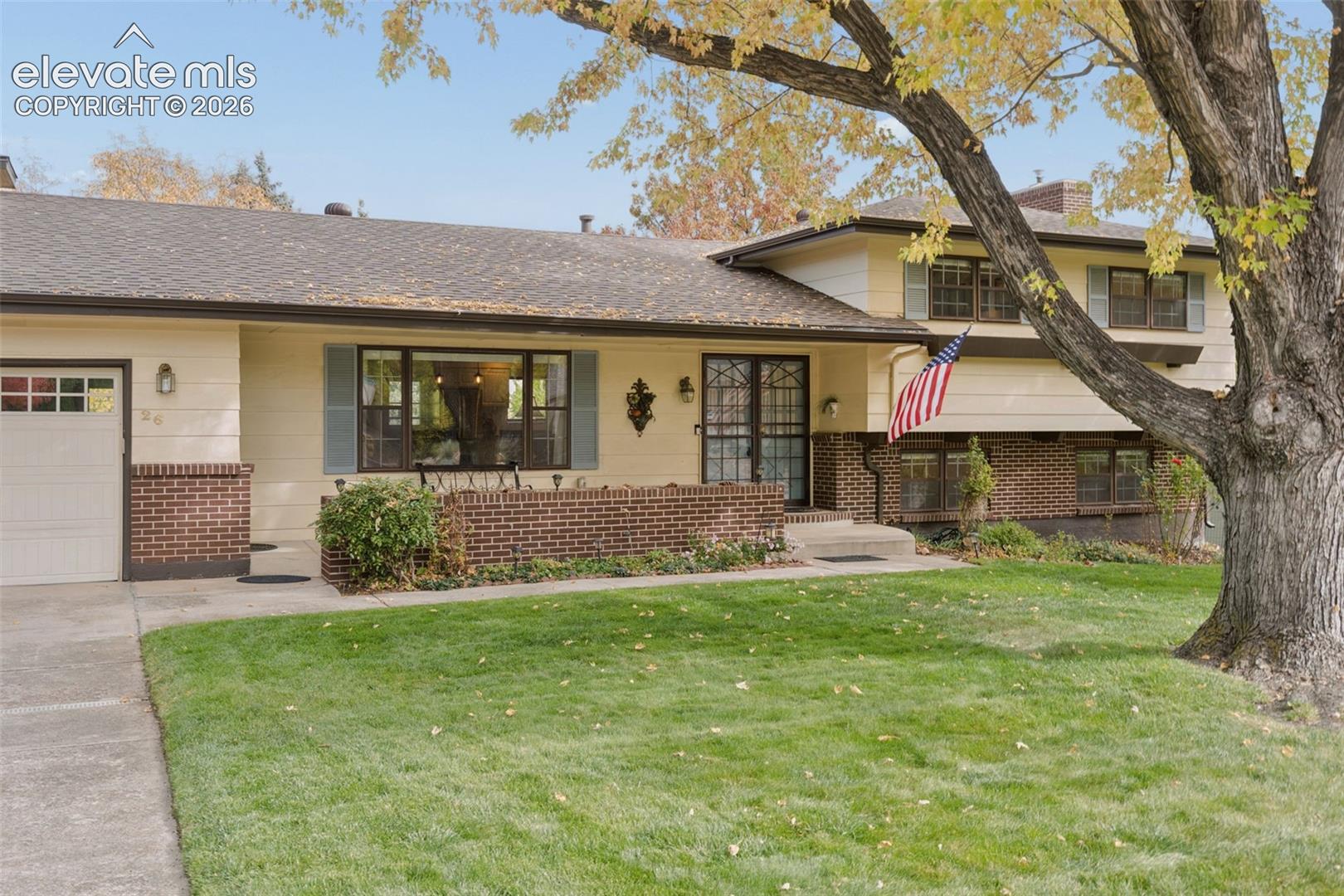 Front yard with brick planter and mature tree