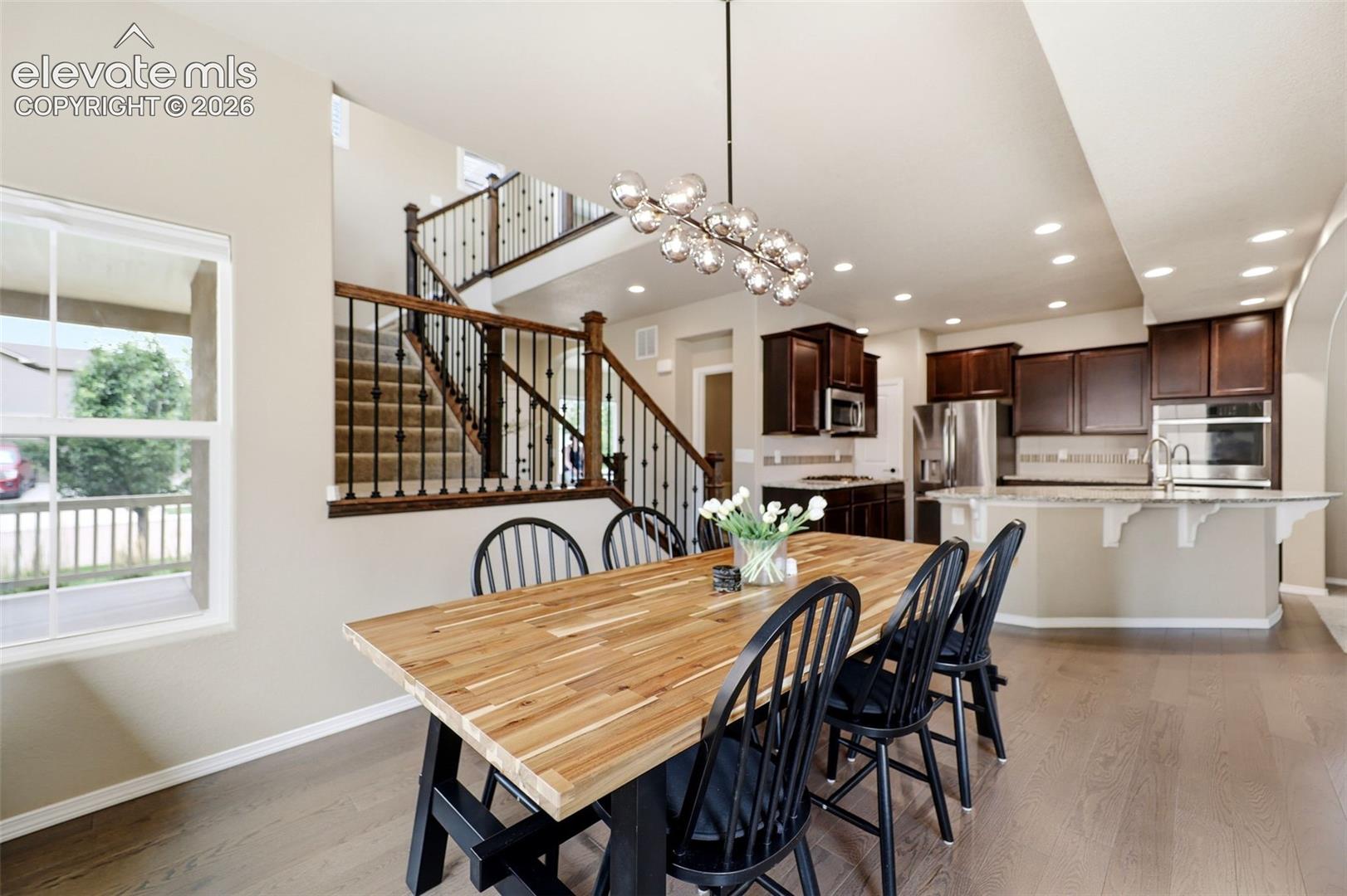 Wood flooring throughout, with a striking open staircase featuring dark wood newel posts and black wrought iron balusters