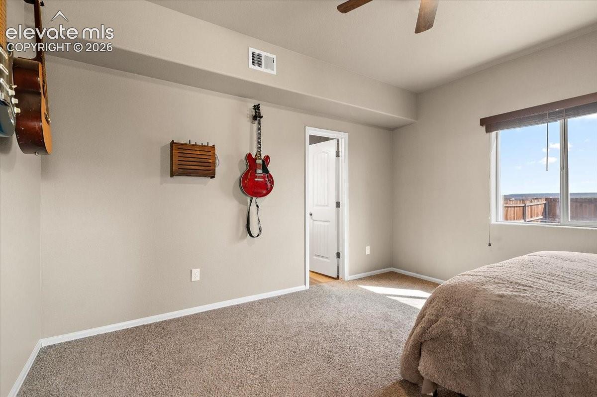 Recessed ceiling, neutral wall paint, light-colored carpet flooring, ceiling fan, and window with outdoor scenery