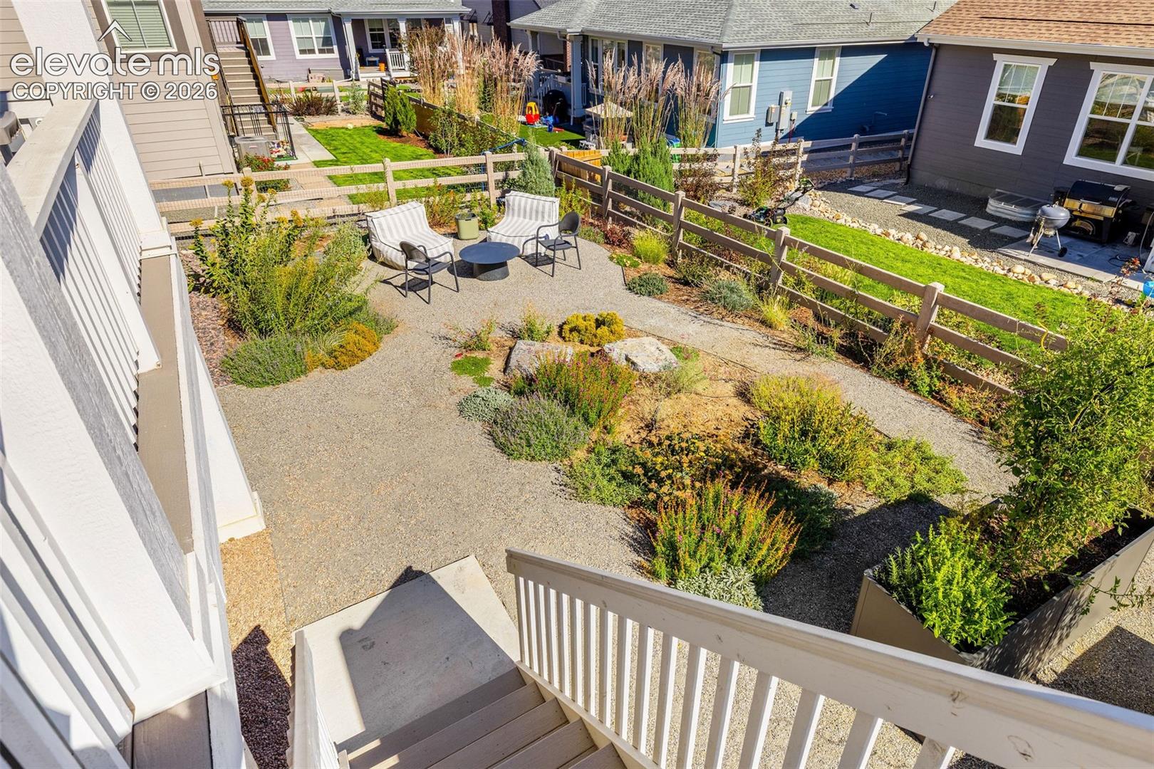Terraced backyard featuring gravel pathways, established plantings, and a wooden fence