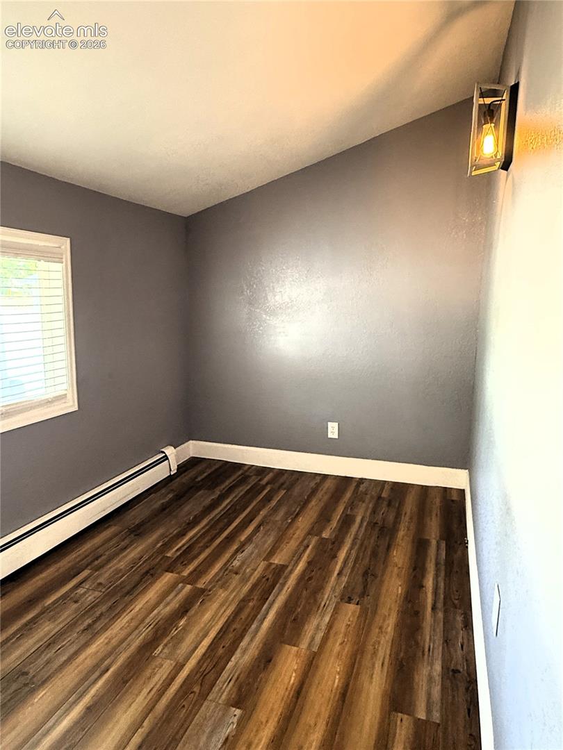 Sloped ceiling featuring wood-finish flooring, neutral wall paint, and a wall-mounted rectangular light fixture