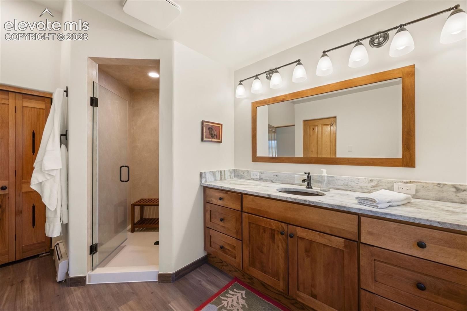 Primary suite with generous walk-in shower with glass enclosure and bench seating.