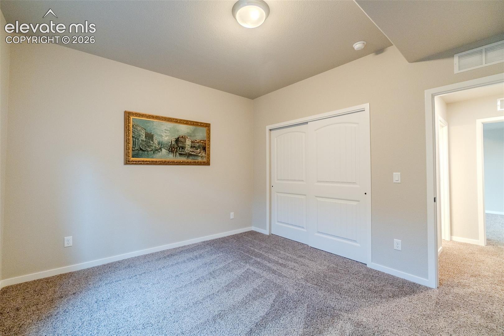 Carpeted room featuring neutral wall tones, white baseboards, and a flush mount ceiling light fixture