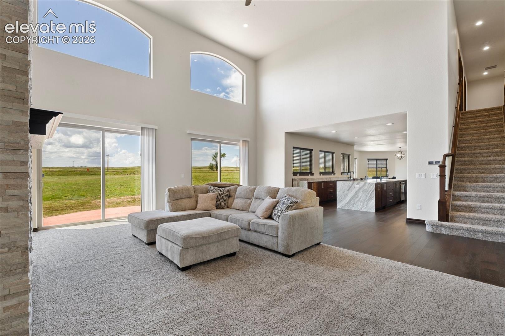 Vaulted living area featuring high arched windows, a stone fireplace, and sliding glass doors to the exterior