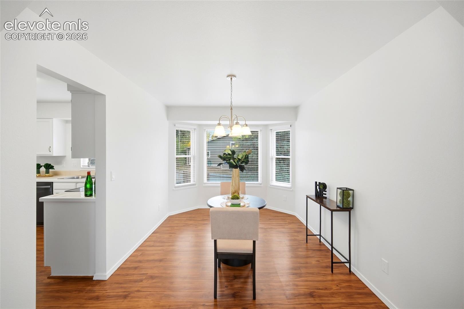 Dining area featuring wood-finish flooring, a three-paneled bay window, and a multi-arm chandelier