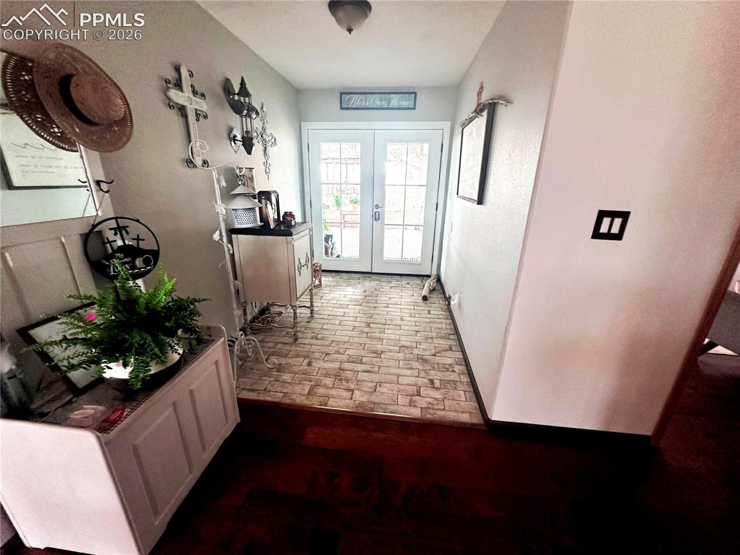 Entrance from covered drive-under breezeway.  Tiled floor joins to natural wood flooring. Opens to dining, living and kitchen areas.