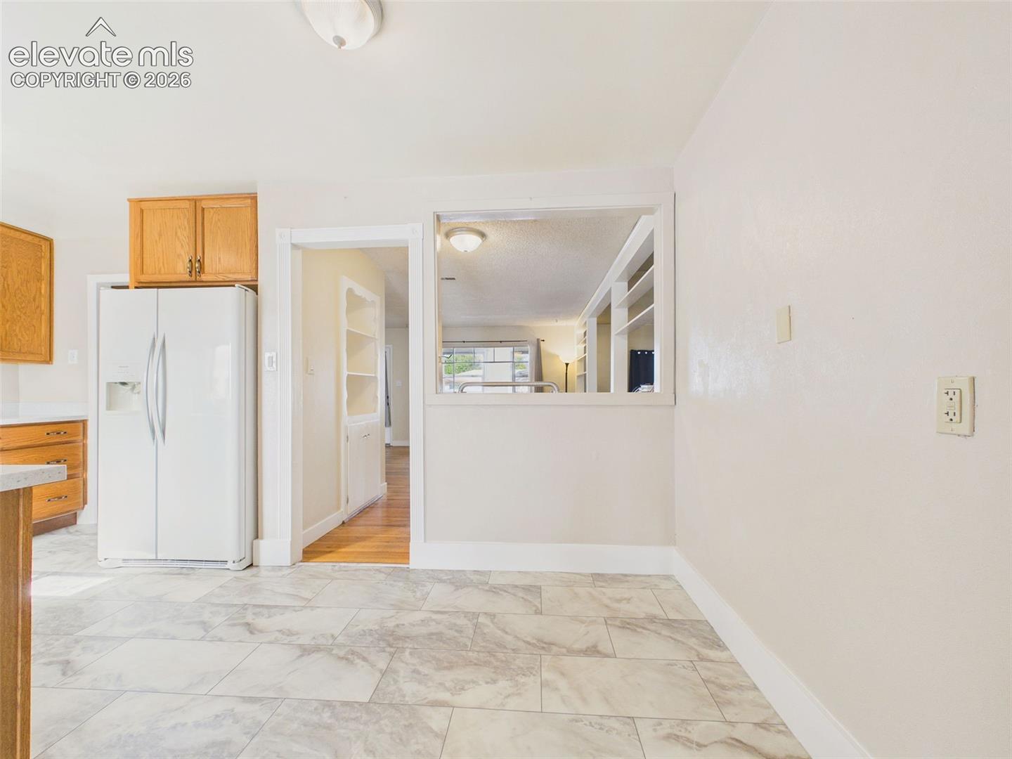 Flexible dining space adjoining the kitchen, featuring tile-look flooring and a pass-through opening overlooking the living room.
