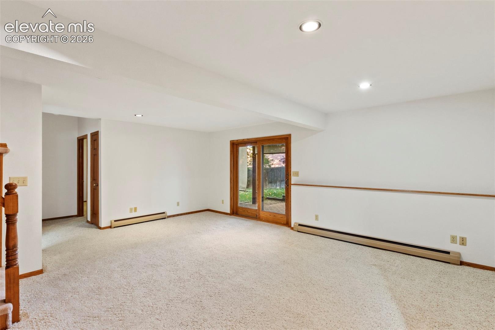 Interior space featuring wall-to-wall carpeting, recessed ceiling lighting, a wood-frame sliding glass door, and wooden door finishes