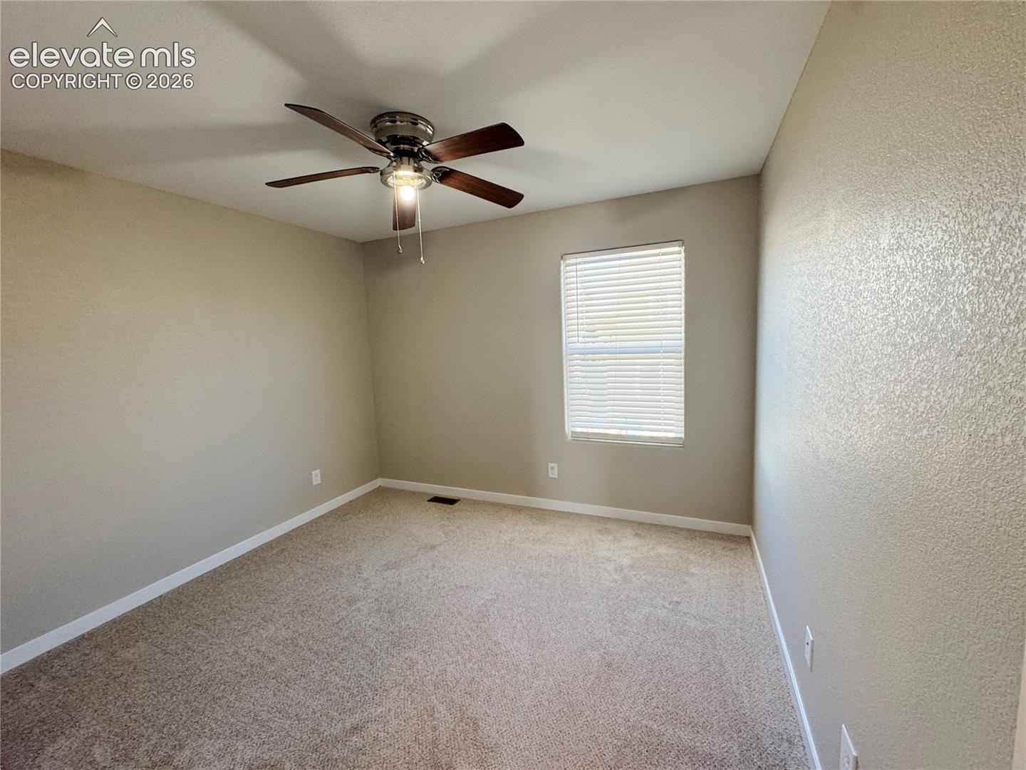 Neutral wall tones, wall-to-wall carpeting, window with blinds, and a multi-blade ceiling fan with integrated lighting