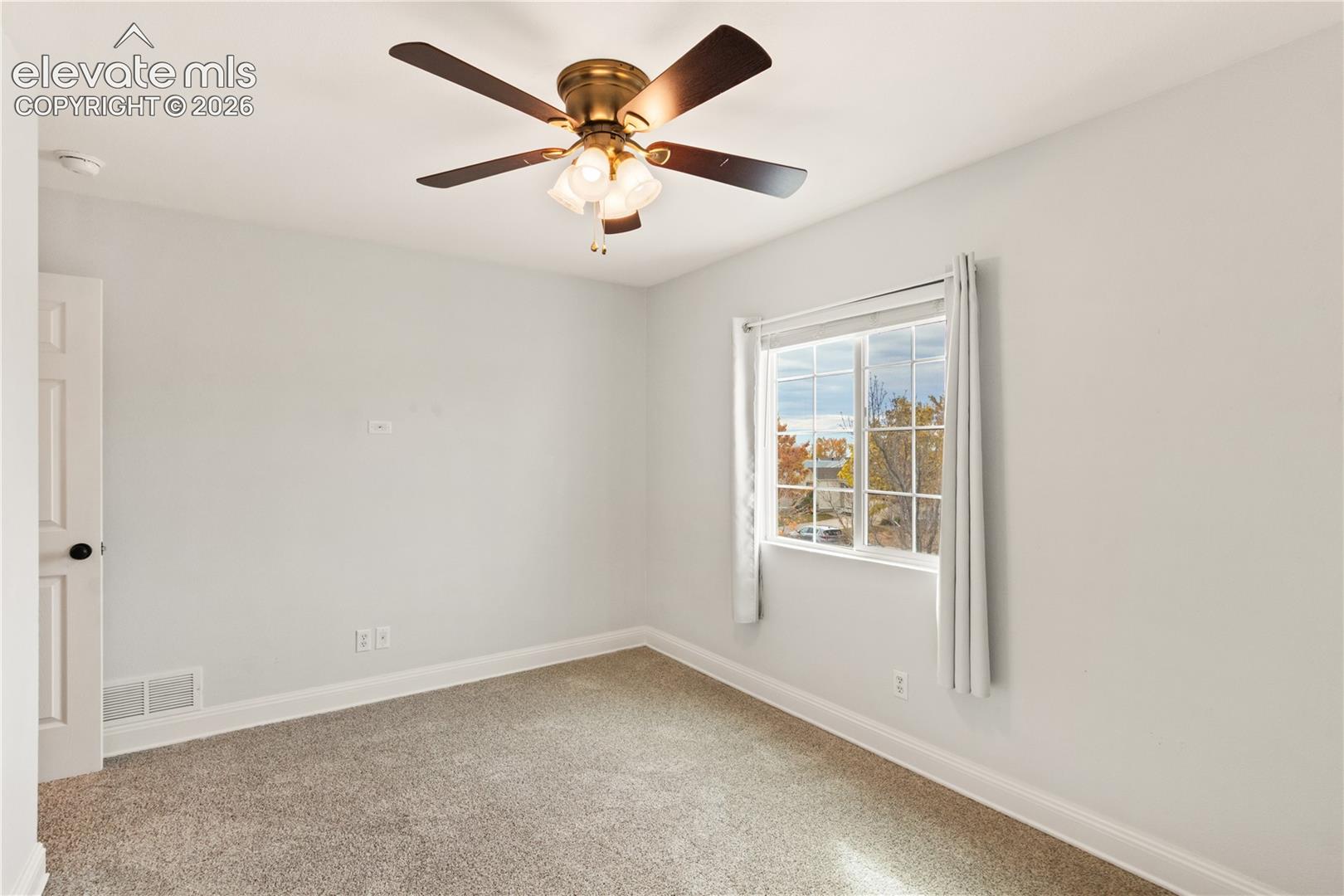Neutral interior featuring wall-to-wall carpeting, a ceiling fan with integrated lighting, and a multi-pane sliding window