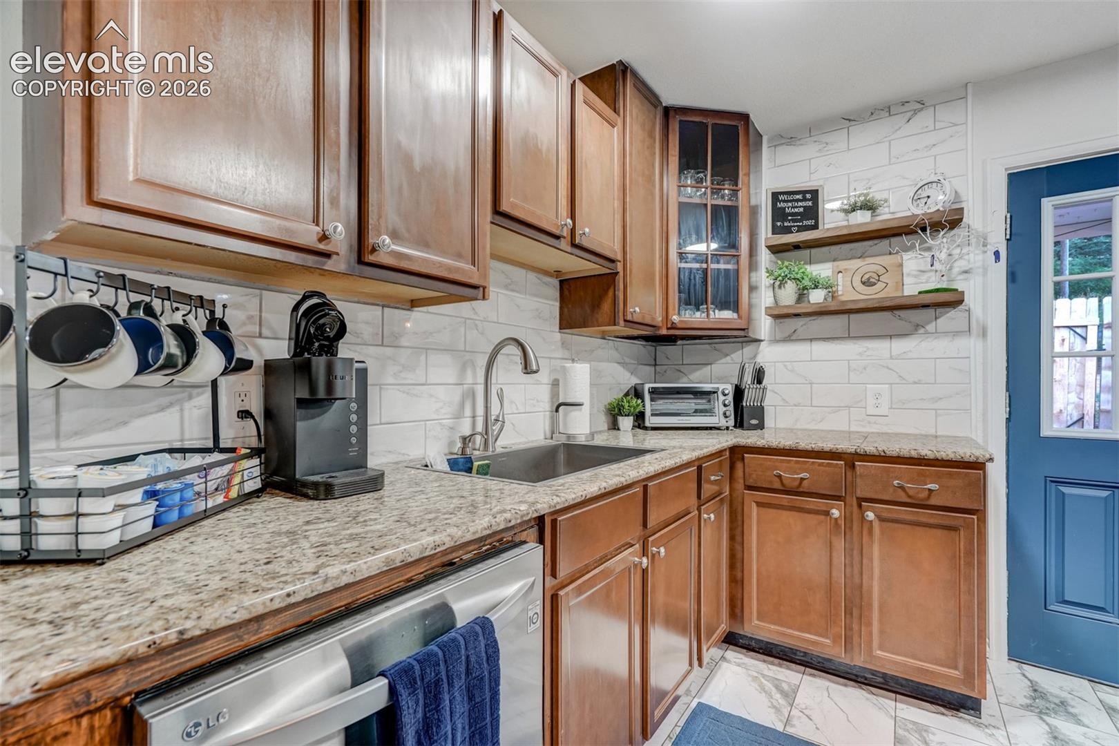 Warm wood cabinetry with brushed nickel hardware and a light stone countertop define this kitchen workspace