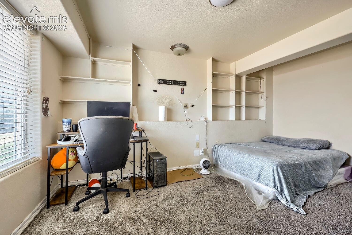 Built-in shelving units, wall-to-wall carpeting, and a window with blinds
