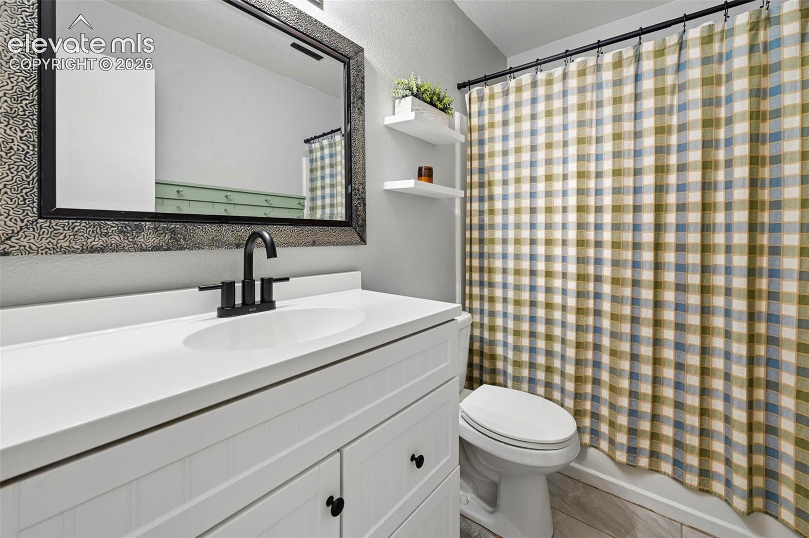 White vanity cabinet with integrated basin, matte black faucet, framed wall mirror, and dual wall-mounted floating shelves