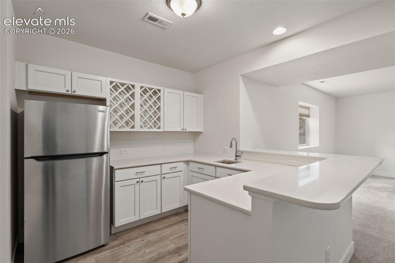 Basement wetbar featuring a full-sized refrigerator