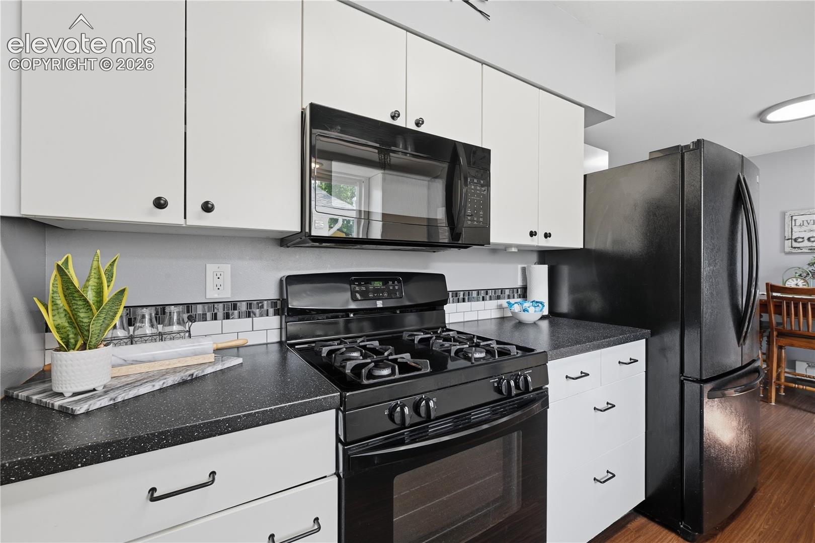 Another view of the kitchen showcases the attractive black appliances, ample counter space, and smart storage throughout.