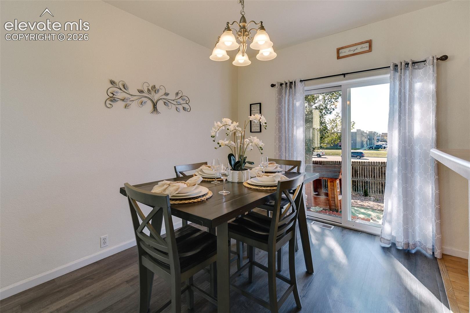 Dining area featuring a contemporary chandelier, wood-finish flooring, and a sliding glass door