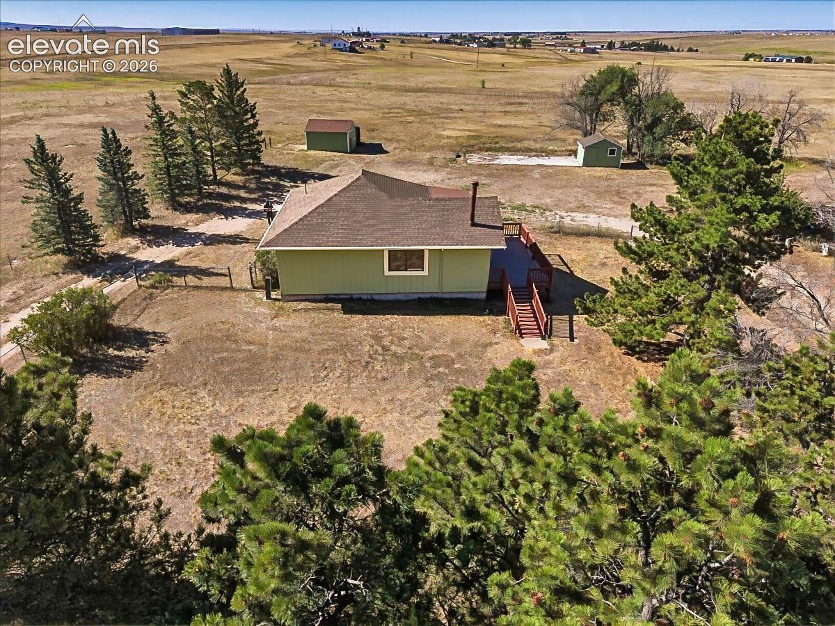 Backyard Aerial – Rear aerial highlights the home's deck, open outdoor space, and the privacy provided by established trees and the surrounding landscape.