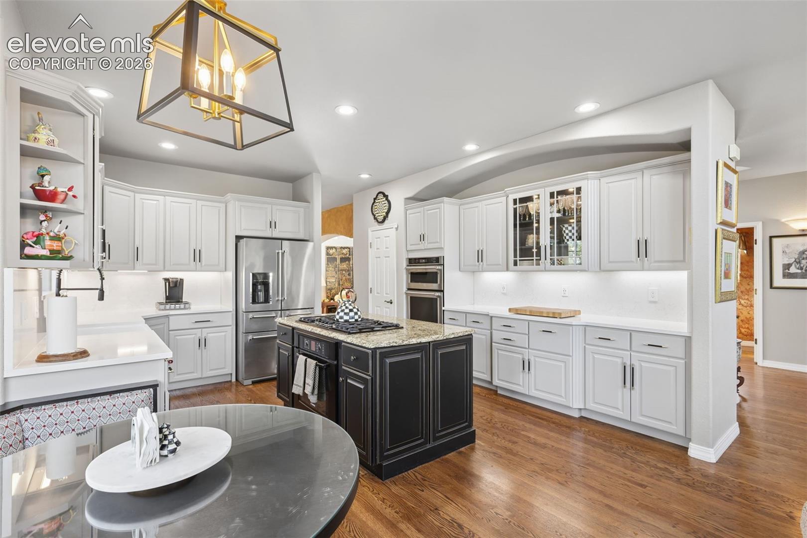 Beautifully remodeled gourmet kitchen with granite, quartz, wood floors, island, and high-end appliances.