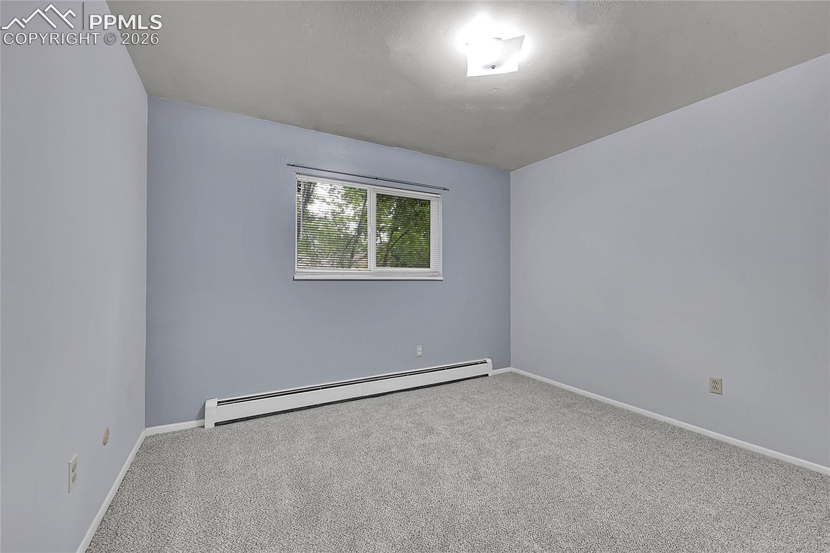 Empty room with a baseboard heating unit and carpet