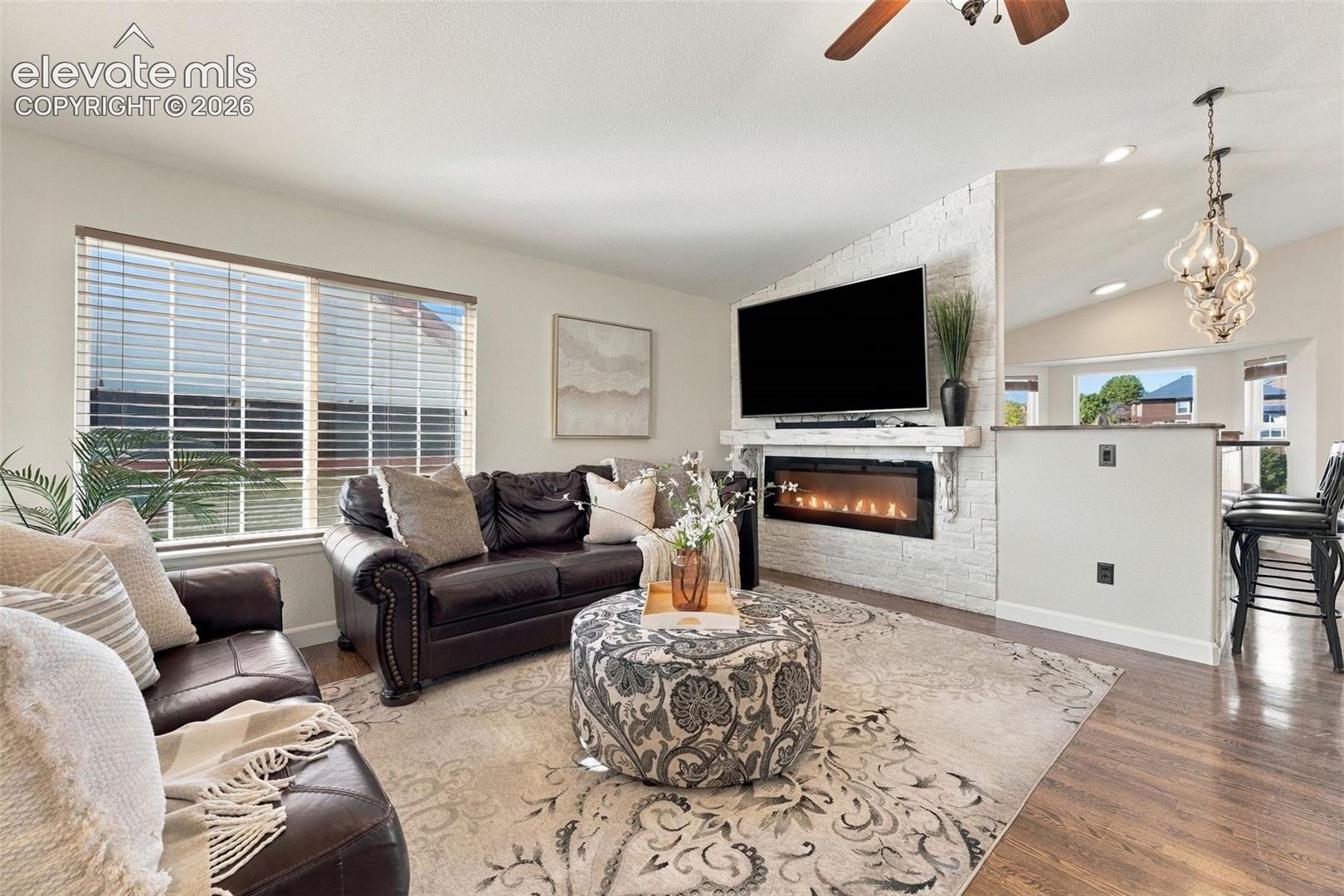 Living area featuring a floor-to-ceiling painted brick fireplace, a built-in linear electric firebox, a substantial wood mantel, recessed lighting, and wood-finish flooring