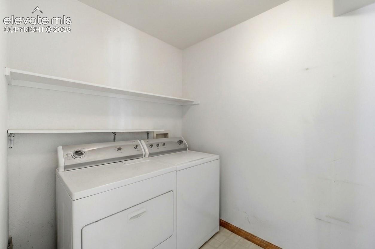 Dedicated laundry area featuring white walls, two integrated white shelves, and neutral-toned flooring
