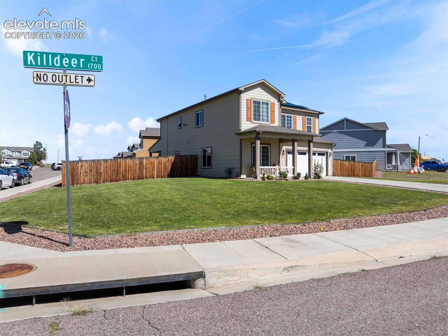 Two-story structure with a covered front porch, two-car garage, and a wood privacy fence