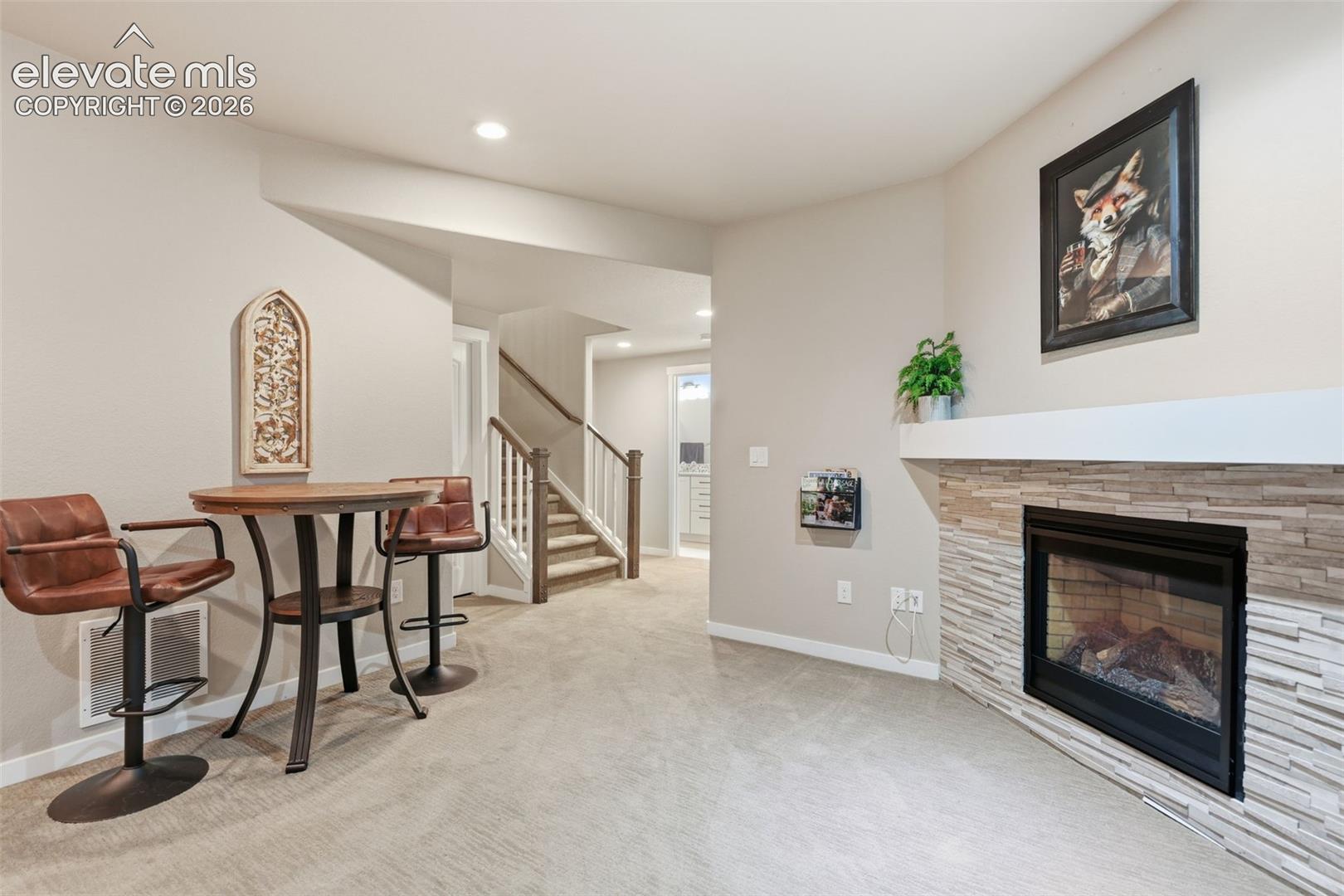 A fireplace with a stacked stone facade and mantel, recessed lighting.