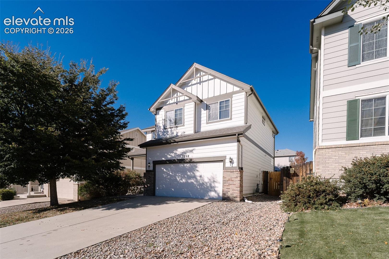Two-story exterior featuring lap siding, board-and-batten accents, decorative gable detailing, masonry base accents, and a two-car attached garage