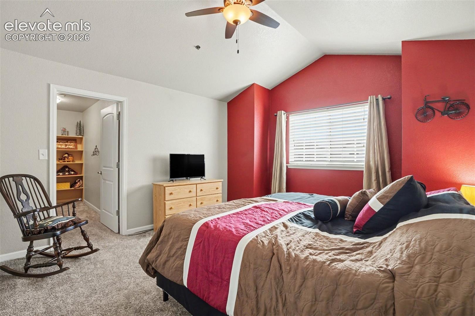 Vaulted ceilings, carpeted flooring, accent wall, ceiling fan with integrated lighting, and horizontal window blinds