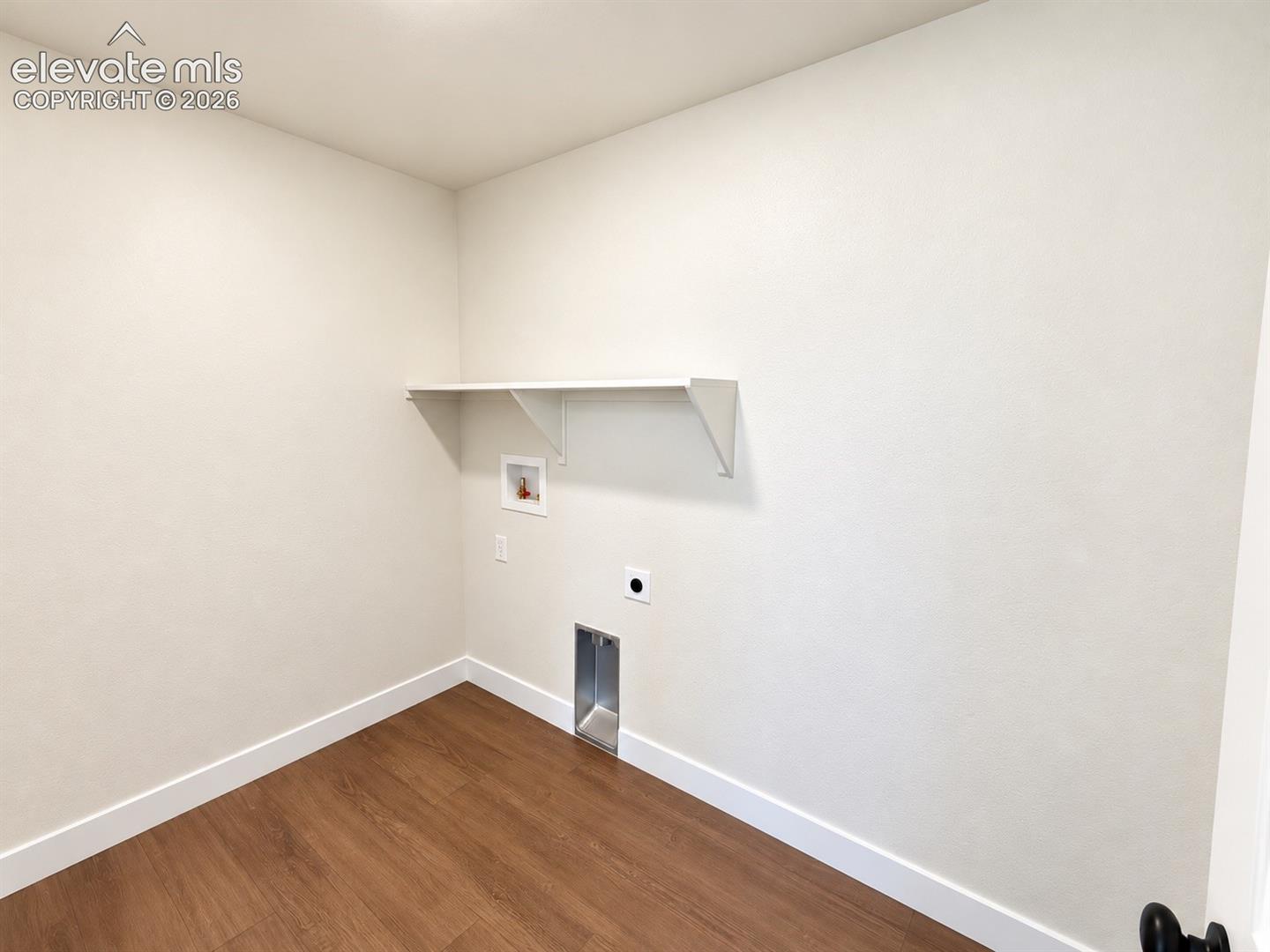 Laundry alcove with wood-finish flooring, a wall-mounted shelf, and appliance hookups