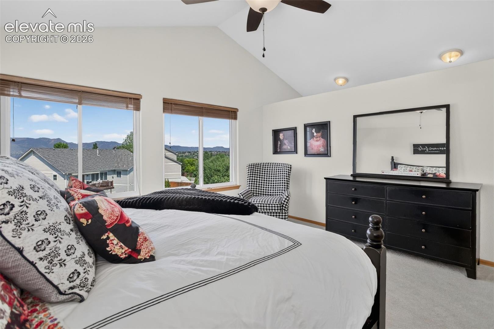 Vaulted ceiling bedroom with large windows showcasing distant landscape